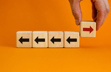 El ele tutuşmuş ahşap blok ve kırmızı ok ters yöne bakan siyah oklar. Eşsiz, farklı, bireysel ve kalabalık konseptinden uzak.