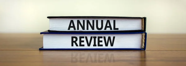 Annual review symbol. Concept words \'annual review\' on books on a beautiful wooden table, white background. Business and annual review concept, copy space.