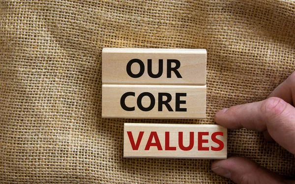 Our core values symbol. Concept words 'our core values' on wooden blocks on a beautiful canvas background. Businessman hand. Business and our core values concept.