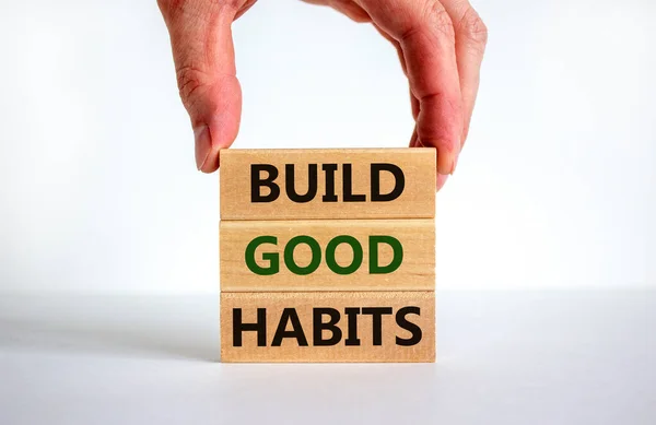 Build good habits symbol. Wooden blocks with words \'build good habits\'. Male hand. Beautiful white background, copy space. Business, psychological and build good habits concept.