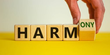 Zarardan armoniye. Erkek el küpü döndürür ve 'zarar' kelimesini 'uyum' a çevirir. Güzel sarı masa, beyaz arka plan. İş ve zarar ya da uyum kavramı. Boşluğu kopyala.