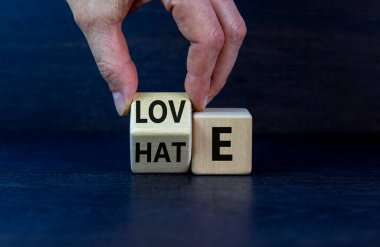 Nefretten aşk sembolüne. El küpü döndürür ve 'nefret' kelimesini 'sevgi' ye çevirir. Güzel, koyu ahşap arka plan, kopyalama alanı. Sevgililer günü ve nefret ya da aşk konsepti.