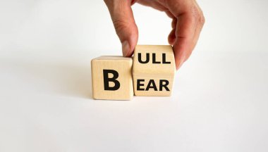 Borsada olumlu bir eğilimin sembolü. İş adamı eli küpü çevirir ve 'ayı' kelimesini 'boğa' ya çevirir. Güzel beyaz arka plan. İş ve ayı kavramı veya boğa kavramı. Boşluğu kopyala.