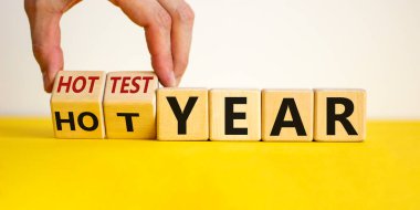 En sıcak yıl ve küresel ısınma kavramı. El küpleri döndürür ve 'sıcak yıl' ı 'en sıcak yıl' a çevirir. Güzel sarı masa, beyaz arka plan. İş ve en ateşli yıl konsepti. Boşluğu kopyala.