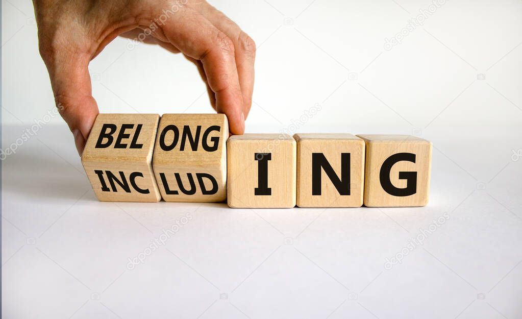 Including or belonging symbol. Businessman hand turns cubes and changes the word 'including' to 'belonging'. Beautiful white background. Business and Including or belonging concept. Copy space.