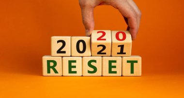 2021 'in sembolü sıfırlandı. İşadamı ahşap küpleri çeviriyor ve '2020' yi sıfırla 'yı' 2021 'e sıfırla' olarak değiştiriyor. Güzel turuncu arkaplan, kopyalama alanı. İş ve 2021 yeni yıl konseptini sıfırladı.