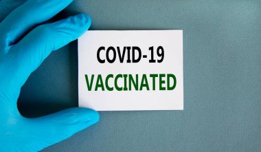 Covid-19 aşı sembolü. Mavi eldiven ve beyaz kart. 'Covid-19 aşıladı' kavramını kullan. Tıbbi ve COVID-19 aşı salgını konsepti. Boşluğu kopyala.