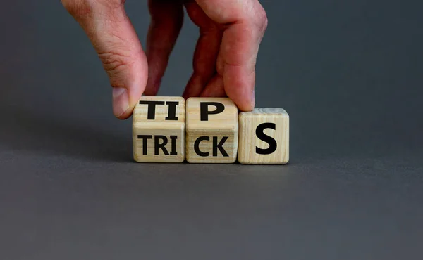 Tips and tricks symbol. Businessman turns cubes and changes the word \'tricks\' to \'tips\'. Beautiful grey background. Business, tips and tricks concept. Copy space.