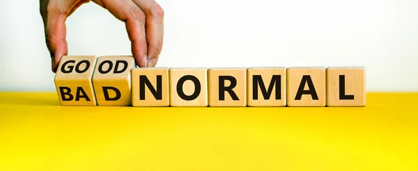 Good vs bad normal symbol. Businessman turns wooden cubes and changes words \'bad normal\' to \'good normal\'. Beautiful yellow table, white background, copy space. Business and good normal concept.