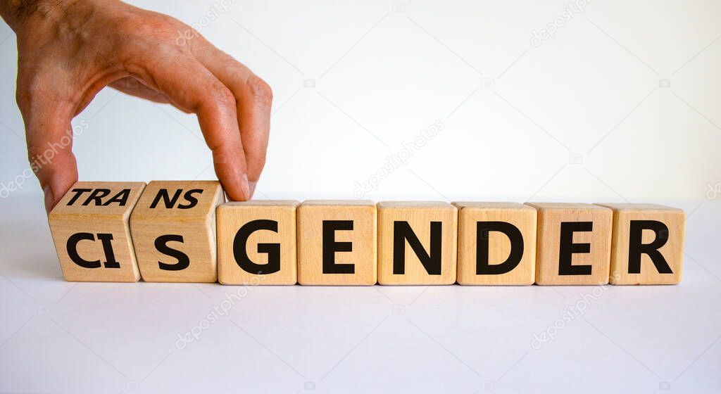 Transgender or cisgender symbol. Male hand flips wooden cubes and changes word 'cisgender' to 'transgender'. Beautiful white background, copy space. Transgender or cisgender concept.