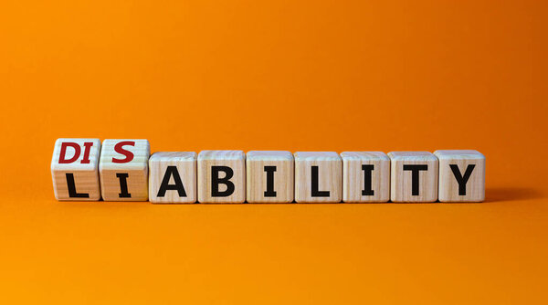 Liability or disability symbol. Turned cubes and changed the word 'liability' to 'disability'. Beautiful orange background. Business, liability or disability concept. Copy space.