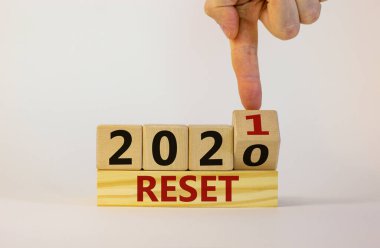 2021 yılının iş konsepti sıfırlandı. İşadamı bir tahta küpü çeviriyor ve '2020' yi sıfırla 'yı' 2021 'e sıfırla' diye değiştiriyor. Güzel beyaz arka plan, kopyalama alanı. İş, 2021 simgesini sıfırla.
