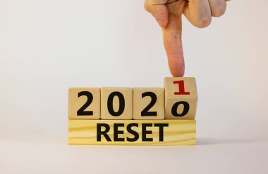 2021 yılının iş konsepti sıfırlandı. İşadamı bir tahta küpü çeviriyor ve '2020' yi sıfırla 'yı' 2021 'e sıfırla' diye değiştiriyor. Güzel beyaz arka plan, kopyalama alanı. İş, 2021 simgesini sıfırla.