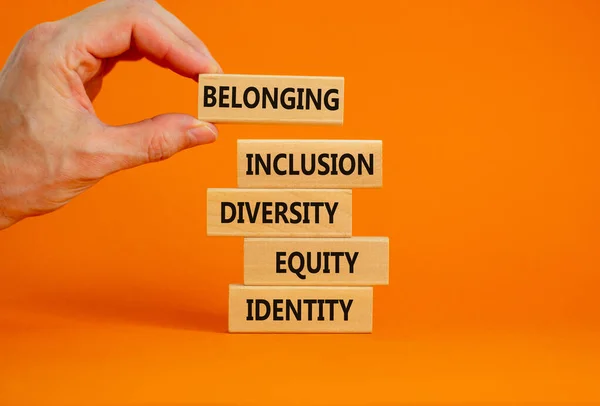 Equity, idenyity, diversity, inclusion, belonging symbol. Wooden blocks with words identity, equity, diversity, inclusion, belonging on beautiful orange background. Inclusion, belonging concept.