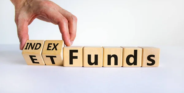 Index funds vs ETF symbol. Businessman turns a cube and changes words 'ETF, Exchange-Traded Fund' to 'Index funds. Beautiful white background, copy space. Business and ETF vs index funds concept.