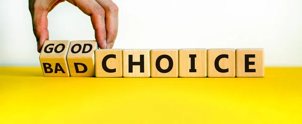 Good or bad choice symbol. Businessman turns wooden cubes and changes words 'bad choice' to 'good choice'. Beautiful yellow table, white background, copy space. Business and good choice concept.