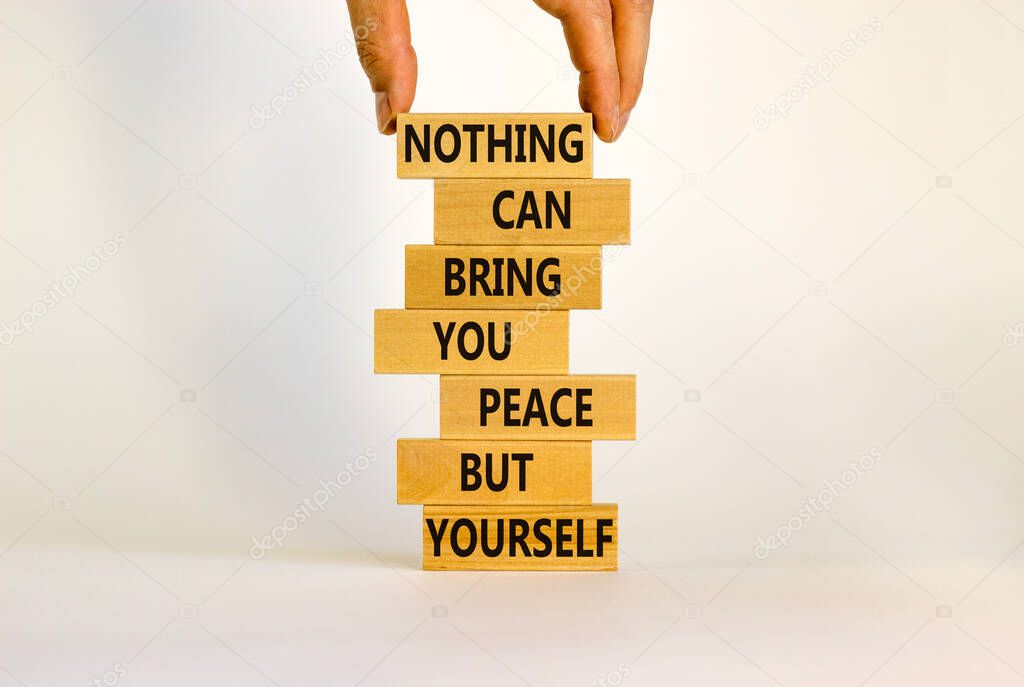 Concept of building success foundation. Businessman hand. Wooden blocks with words nothing can bring you peace but yourself. Beautiful white background, copy space. Business and motivational concept.