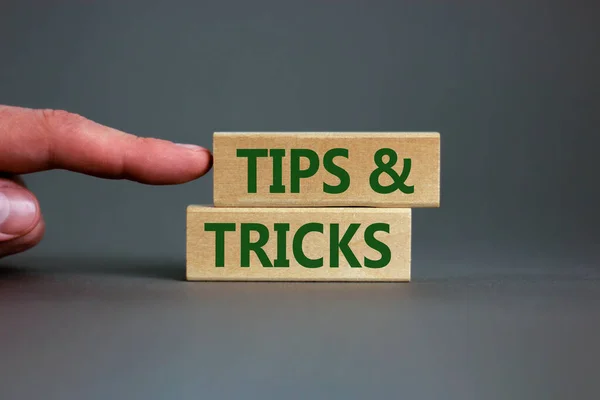 Tips and tricks symbol. Wooden blocks with words 'Tips and tricks'. Beautiful grey background. businessman hand. Business, tips and tricks concept. Copy space.
