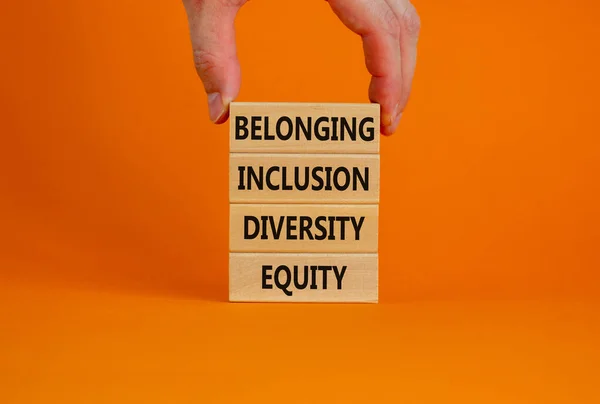 Equity, diversity, inclusion and belonging symbol. Wooden blocks with words equity, diversity, inclusion, belonging on beautiful orange background. Diversity, equity, inclusion and belonging concept.