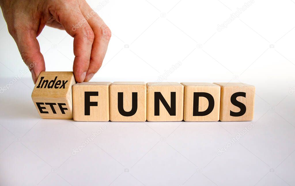 Index funds vs ETF symbol. Businessman turns a cube and changes words 'ETF' to 'Index funds. Beautiful white background, copy space. Business and ETF and index funds concept.