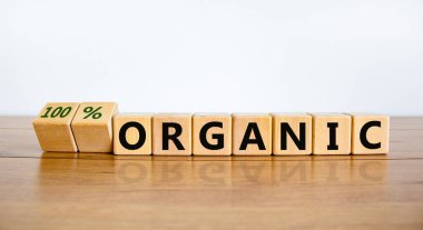 Yüzde yüz organik sembol. Tahta küpleri çevirdim ve 'organik' ile '% 100 organik' kelimelerini değiştirdim. Güzel ahşap masa, beyaz arka plan, fotokopi alanı. İş, sağlıklı yaşam tarzı organik konsept.