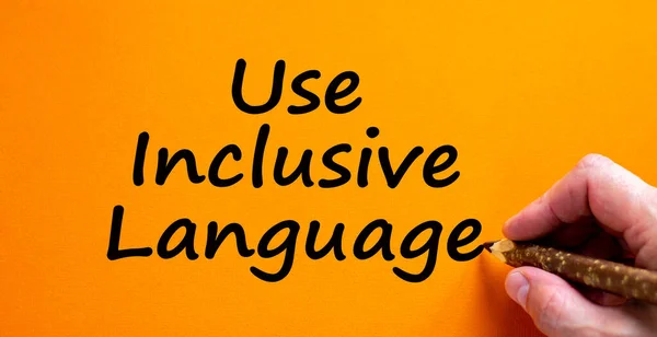 Use inclusive language symbol. Hand writing \'Use inclusive language\', isolated on orange background. Business, inclusion and use inclusive language concept. Copy space.