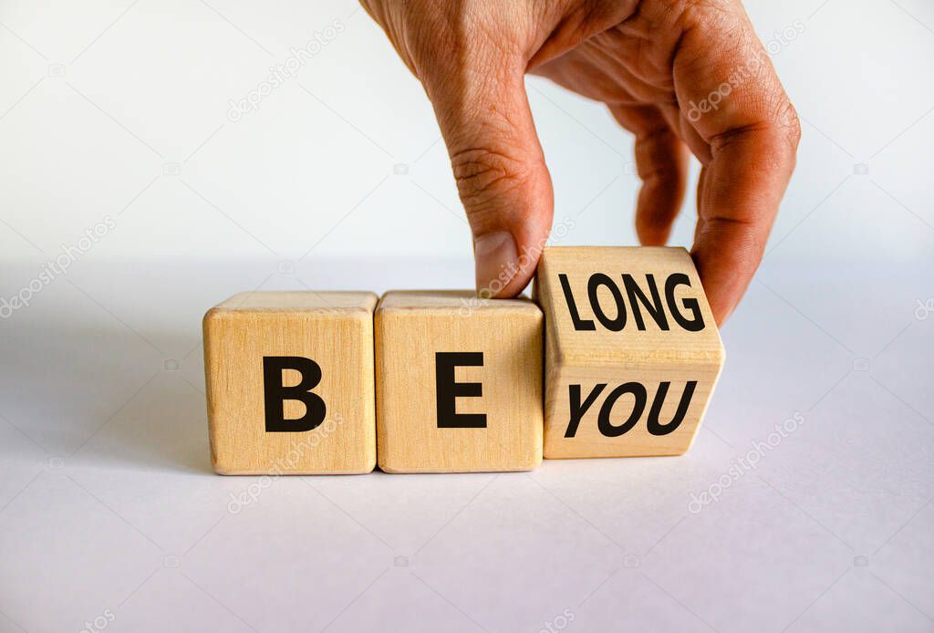 Be you, belong symbol. Businessman hand turns a cube and changes words 'be you' to 'belong'. Beautiful white background. Business, belonging and be you, belong concept. Copy space.