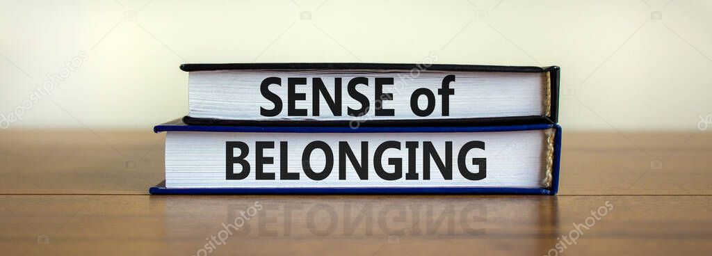 Sense of belonging symbol. Books with words 'sense of belonging' on beautiful wooden table, white background. Business, sense of belonging concept. Copy space.