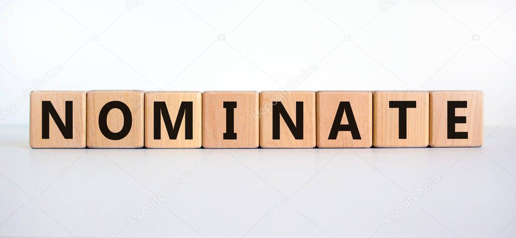 Nominate symbol. Wooden cubes with word 'nominate'. Beautiful white background. Business, psychology and nominate concept. Copy space.