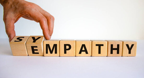 Симпатия или эмпатия. Бизнесмен превращает деревянные кубики и превращает слово "эмпатия" в "сочувствие". Красивый белый фон. Принято. Концепция психологии, симпатии или эмпатии.