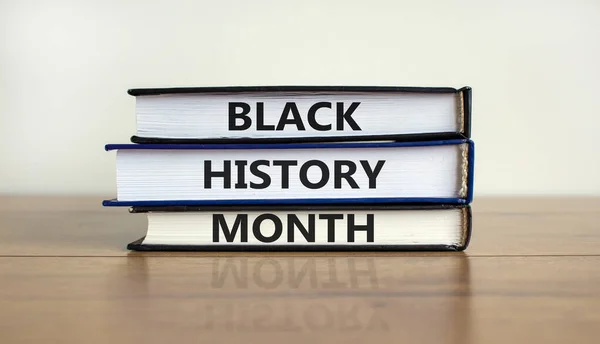 Black history month symbol. Books with words 'Black history month'. Beautiful wooden table, white background. Black history month concept. Copy space.