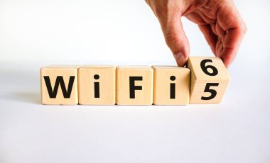 Wi-Fi 5 ya da 6 sembolü. İşadamı tahta küpü çeviriyor ve Wi-Fi 5 'i Wi-Fi 6 olarak değiştiriyor. Güzel beyaz arka plan, kopyalama alanı. İş, teknoloji ve WiFi 5 'ten WiFi 6 konseptine.
