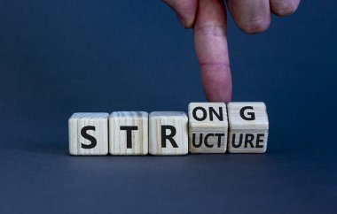 Güçlü yapı sembolü. İşadamı 'güçlü yapı' kelimesiyle tahta küplere dönüşür. Güzel gri arkaplan, kopyalama alanı. İş ve güçlü yapı kavramı.