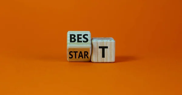 Time to best start symbol. Turned a wooden cube with words \'best start\'. Beautiful orange table, orange background, copy space. Business and best start concept.