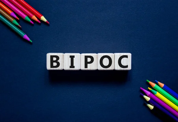 BIPOC symbol. Abbreviation BIPOC, black, indigenous and people of color on wooden cubes. Beautiful grey background. Copy space. Business and BIPOC, black, indigenous and people of color concept.