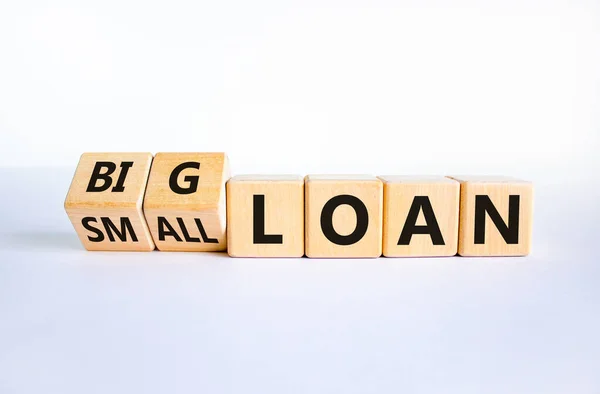 Big or small loan symbol. Turned wooden cubes and changed words 'small loan' to 'big loan'. Beautiful white table, white background, copy space. Business and big or small loan concept.