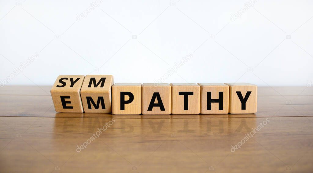 From empathy to sympathy. Turned cubes and changed the word 'empathy' to 'sympathy'. Beautiful wooden table, white background. Copy space. Psychological and empathy or sympathy concept.
