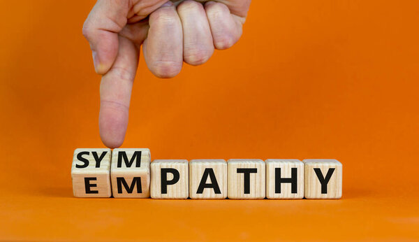 От сочувствия к сочувствию. Бизнесмен превращает кубики и меняет слово "сочувствие" на "сочувствие". Красивый оранжевый фон. Принято. Концепция психологии и эмпатии или симпатии.