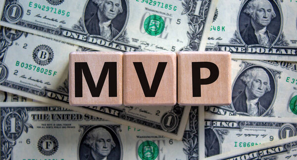 MVP, minimum viable product symbol. Wooden cubes with the word MVP, minimum viable product. Beautiful background from dollar bills. Business and MVP, minimum viable product concept, copy space.