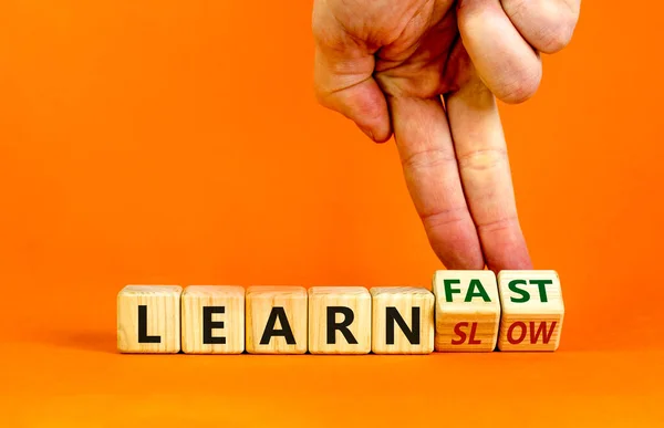 Learn slow or fast symbol. Businessman turns wooden cubes and changes words \'learn slow\' to \'learn fast\'. Beautiful orange background, copy space. Business and learn slow or fast concept.