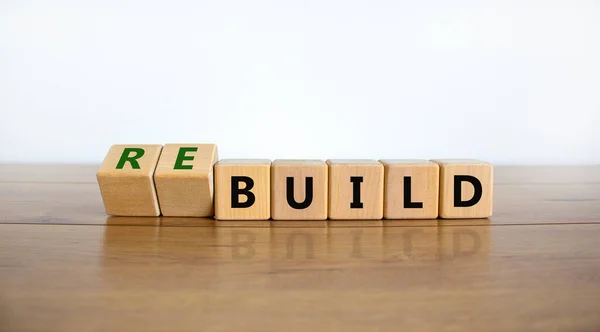Time to rebuild symbol. Turned wooden cubes and changed the word \'build\' to \'rebuild\'. Beautiful wooden table, white background. Business, build or rebuild concept. Copy space.