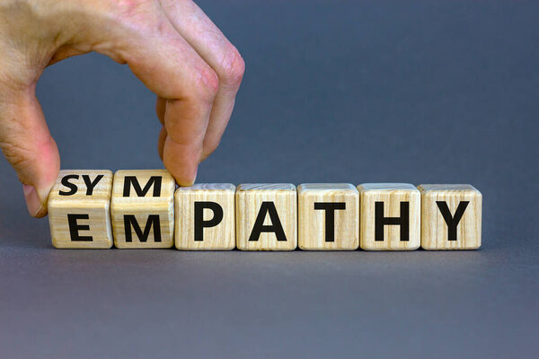 От сочувствия к сочувствию. Бизнесмен превращает кубики и меняет слово "сочувствие" на "сочувствие". Красивый серый фон. Принято. Концепция психологии и эмпатии или симпатии.