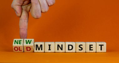 Yeni vs eski zihniyet sembolü. İş adamı ahşap küpü değiştiriyor ve 'eski zihniyet' kelimesini 'yeni zihniyet' olarak değiştiriyor. Güzel turuncu arka plan. İş, yeni ya da eski düşünce tarzı. Boşluğu kopyala.