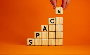 Uzay Komitesi sembolü. Sözcükler içeren tahta küpler, güzel turuncu arka planda özel amaçlı satın alma şirketleri, kopyalama alanı. İşadamı eli. İş ve Uzay Konsepti.