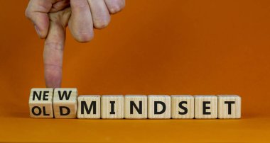 Yeni vs eski zihniyet sembolü. İş adamı ahşap küpü değiştiriyor ve 'eski zihniyet' kelimesini 'yeni zihniyet' olarak değiştiriyor. Güzel turuncu arka plan. İş, yeni ya da eski düşünce tarzı. Boşluğu kopyala.