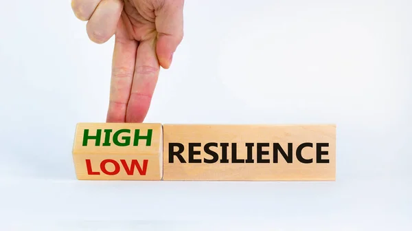 High or low resilience symbol. Businessman flips wooden cubes and changes words \'resilience low\' to \'resilience high\'. Beautiful white background, copy space. Business, high resilience concept.