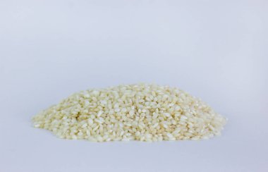 Pişmemiş arborio pilavı. Beyaz arka planda risotto pilavı. Beyaz üzerine izole edilmiş Arborio beyaz pirinç yığını. Arborio 'nun pirinç çeşitlerinin arka planı.