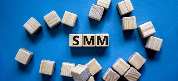 SMM, social media marketing symbol. Wooden cubes with word \'SMM - social media marketing\' on beautiful blue background, copy space. Business, SMM - social media marketing concept.