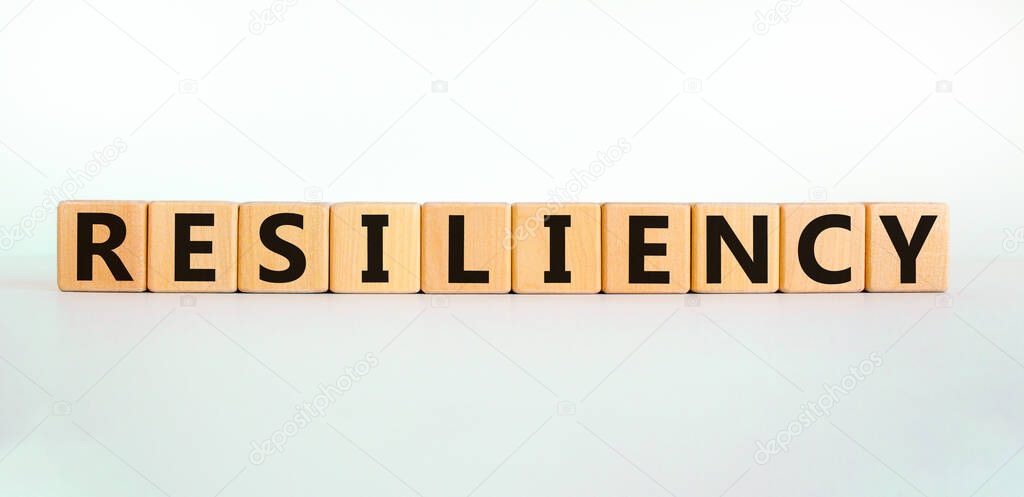 Resiliency symbol. Word 'Resiliency' written on wooden blocks. Copy space. Beautiful white table, white background. Business and resiliency concept.