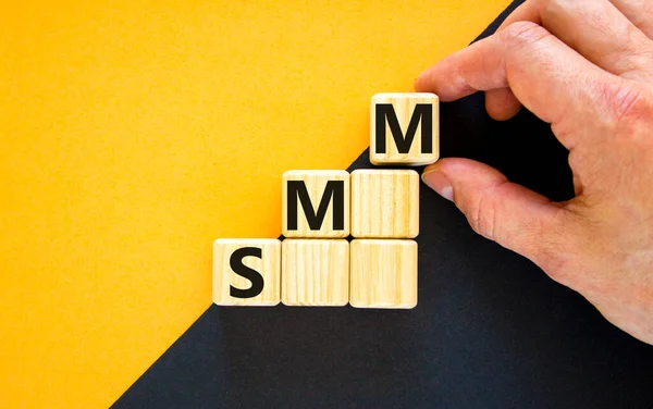 SMM, social media marketing symbol. Wooden cubes with word 'SMM, social media marketing' on beautiful yellow background, copy space. Businessman hand. Business, SMM - social media marketing concept.
